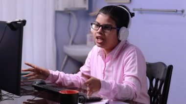 Pembe gömlekli Hintli kadın öğretmen evde bilgisayar konferansı yapıyor.