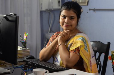 Evde bilgisayarla çalışan sari giyen Hintli kadın, ev konsepti üzerine çalışıyor.