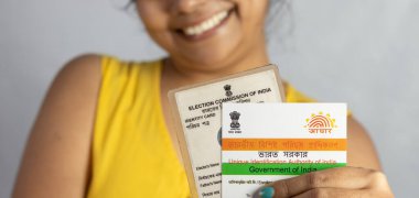 Birbhum, Batı Bengal / Hindistan - 21 Aralık 2021: Aadhaar ve Hintli genç bir kadın tarafından elde tutulan seçici oy kartı
