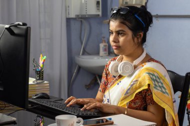 Sari giyen Hintli kadın evden bilgisayarla çalışıyor, ev konseptiyle çalışıyor.