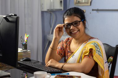 Evde bilgisayarla çalışan sari giyen Hintli kadın, ev konsepti üzerine çalışıyor.