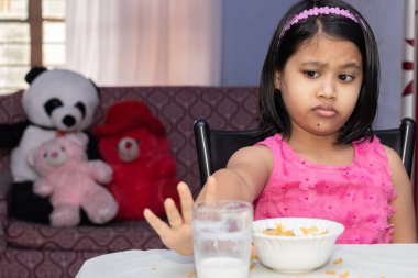 Eksik mısır gevreği ve sevmediğini gösteren sütle beslenen Hintli bir kıza odaklan.