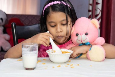 Hintli bir kız çocuğu süt ile mısır gevreği yiyor.