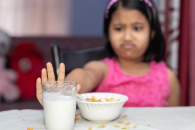Eksik mısır gevreği ve sevmediğini gösteren sütle beslenen Hintli bir kıza odaklan.