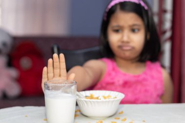 Eksik mısır gevreği ve sevmediğini gösteren sütle beslenen Hintli bir kıza odaklan.