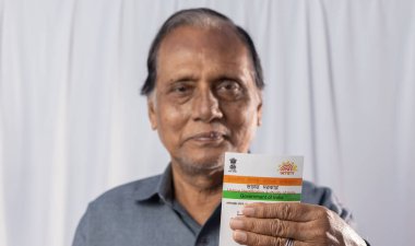 Birbhum, Batı Bengal / Hindistan - 15 Mart 2022: Gülen suratlı yaşlı bir Hintli adamın elinde tuttuğu Aadhaar kartı üzerine seçici odaklanma