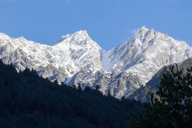 Snow peak mountain range glowing in sunlight with clear blue sky
