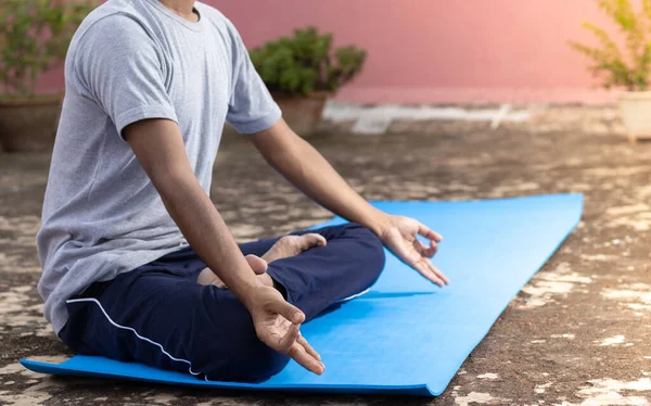 An unidentifiable Indian male practicing yoga on yoga mat outdoors