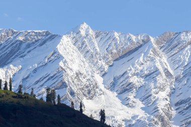Close up of snow peak mountain range glowing in sunlight with clear blue sky