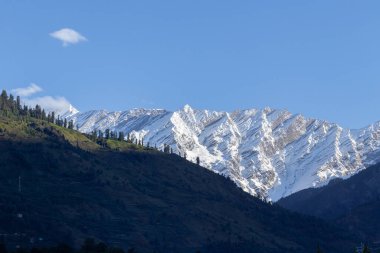 Snow peak mountain range glowing in sunlight with clear blue sky