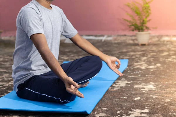 An unidentifiable Indian male practicing yoga on yoga mat outdoors