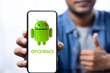 Elinde Hintli gülümseyen bir erkek tarafından tutulan android logosuyla akıllı bir telefon ekranını kapat.