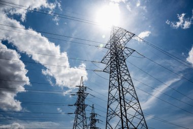 Mavi gökyüzü arasında yüksek voltajlı elektrik direkleri.