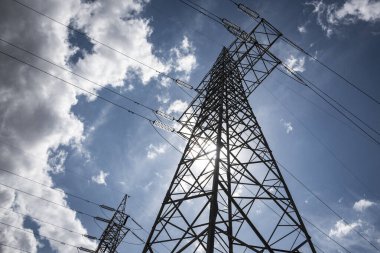 Mavi gökyüzü arasında yüksek voltajlı elektrik direkleri.