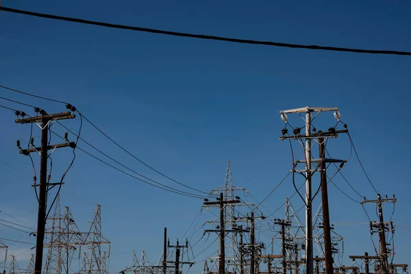 High voltage electricity pylons among a blue sky.