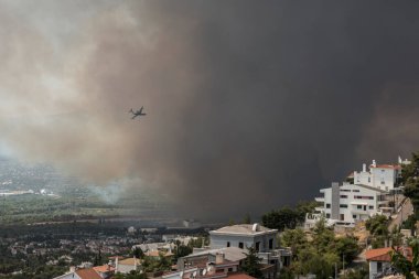 Atina, Yunanistan-03 Ağustos 2021: Bir itfaiyeci Beriev 200 Atina 'nın kuzeyindeki Varympompi banliyösündeki orman yangınının üzerinden uçtu.