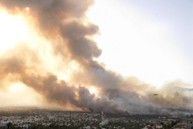Atina, Yunanistan, 03 Ağustos 2021: Atina 'nın kuzeyindeki Varympompi bölgesinde büyük çaplı bir yangının panoramik görüntüsü. Bir itfaiyeci Beriev 200 dumanın içinden uçuyor kalın duman pirokümülüs fenomenini gösteriyor. 