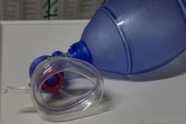 Tıbbi enstrüman masasına silikon yüz maskesi takılmış mavi bir Ambu torbasının (Resuscitator) yakın görüntüsü. Bu tıbbi ekipman solunum bozukluklarını tedavi etmek için kullanılır..