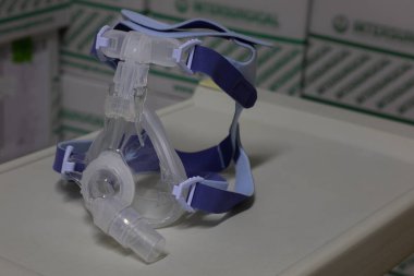 Zararsız havalandırma terapisi için zararsız tam yüz havalandırma maskesi (NIV maskesi) bir enstrüman masasına yerleştirilir. Bu tıbbi ekipman solunum bozukluklarını ve viral zatürreeyi tedavi etmek için kullanılır.