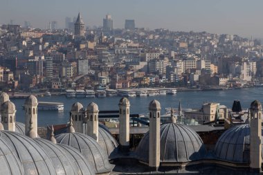 Panoramic urban cityscape of Istanbul from the rooftop of Suleymaniye Mosque. There are visible domes and chimneys of the mosque; Galata tower, Karakoy district, Golden Horn strait and sea transport.