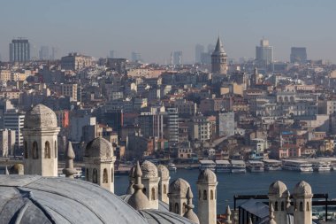 Panoramic urban cityscape of Istanbul from the rooftop of Suleymaniye Mosque. There are visible domes and chimneys of the mosque; Galata tower, Karakoy district, Golden Horn strait and sea transport.