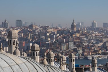 Panoramic urban cityscape of Istanbul from the rooftop of Suleymaniye Mosque. There are visible domes and chimneys of the mosque; Galata tower, Karakoy district, Golden Horn strait and sea transport.