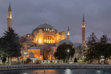 Hagia Sophia and the large round fountain are located on the Square of Sultan Ahmed. The temple has high minarets and several large domes. In the dusky evening, the building is illuminated nicely. 