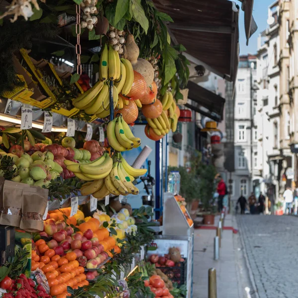 Various fruits and vegetables: bananas, apples, pomelo, oranges, tangerines, tomatoes, garlic, herbs and others lie and hang on the counter of a street vendor on the street of Istanbul.