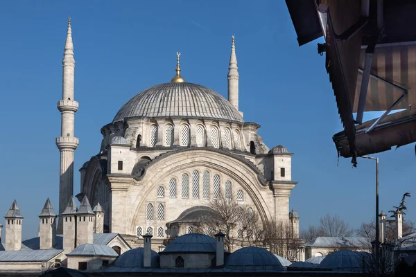The upper part of the mosque is made of white stone. At the very top there are a large dome and golden islamic crescent, below there are small domes and conical chimneys. The mosque has high minarets.