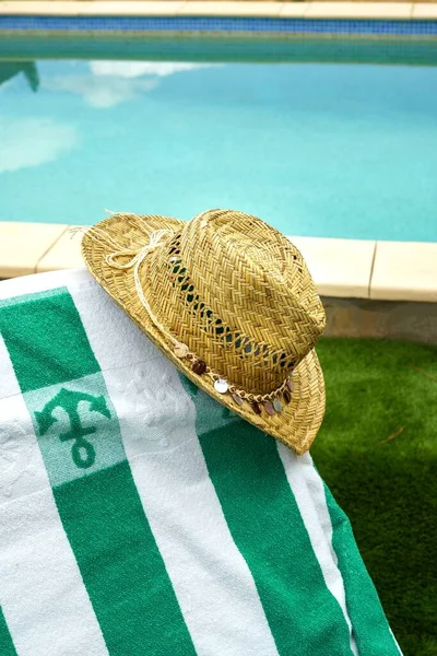 Straw hat on a hammock with a towel, pool in the background. Relaxation and tranquility on vacations