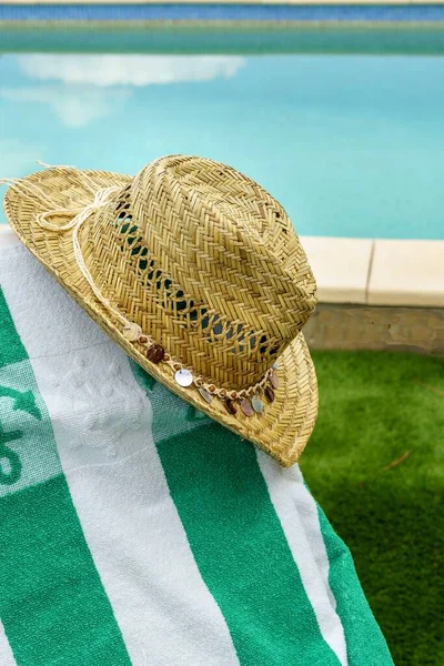 Straw hat on a hammock with a towel, pool in the background. Relaxation and tranquility on vacations
