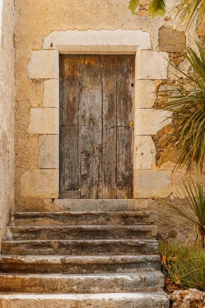 Old rustic wooden door and stairs leading to a farmhouse.