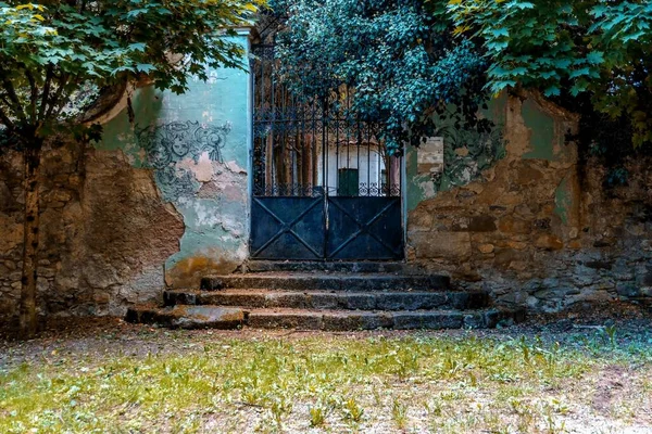 Rusty metal door. Entrance with stairs to cemetery