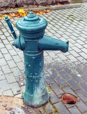 Şehrin kaldırımında eski metal bir su pompası ve sapı var. Panevezys Litvanya 23 Ekim 2021