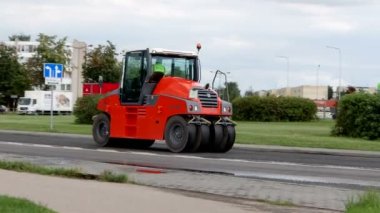 Lastik asfalt sıkıştırma tekerli bir traktör yazın yol yüzeyini geliştirir. Panevezys, Litvanya 8d. Ağustos. 2021