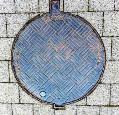 HYDROTEC adındaki fayanslar arasındaki kaldırımda rögar kapağı var. Şehir Panevezys Litvanya 21 Kasım