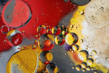 A background of bubbles of various colors and shapes in oil and water with reflections of light and color