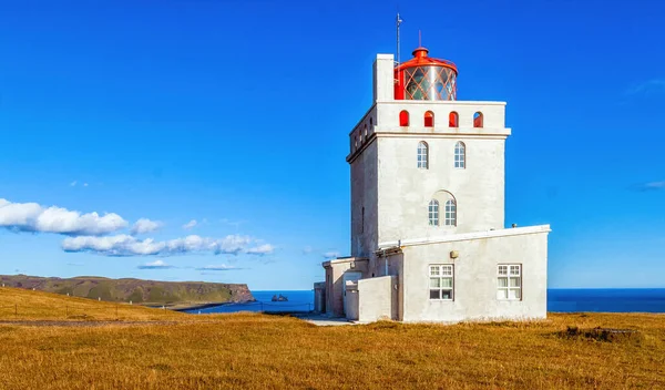 Dyrholaey Kayası 'nın tepesinde büyük bir deniz feneri İzlanda' da gökyüzü ve okyanusun arka planına karşı..