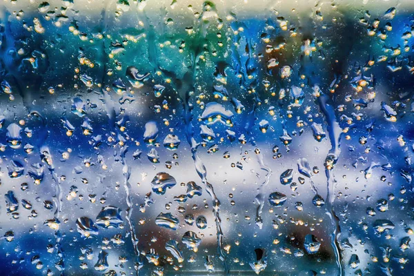 雨天窗玻璃上的雨滴造成了一种抽象的模糊的色彩背景 — 图库照片