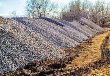 Yeni bir gelecek parkı için ilkbaharda güneşin altında ezilmiş taş yığınları.