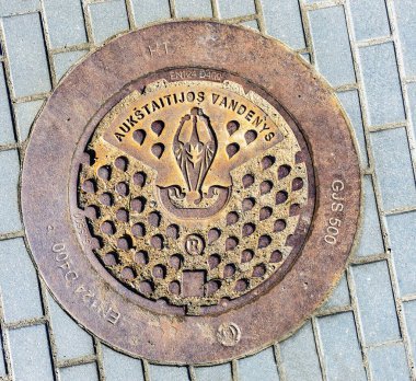 Asfalt blokları arasındaki kanalizasyon kapağı, üst manzara. Panevezys, Litvanya 28 Mart 2022