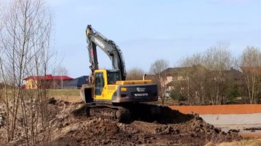 Şehrin kenar mahallelerinde, güçlü bir kazıcı VOLVO 'nun toprağı kazdığı bir park hazırlanıyor. Panevezys, Litvanya 15 Nisan 2022