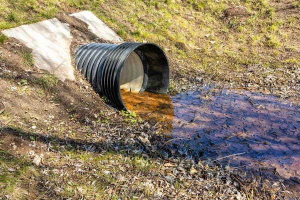 Parkın altındaki yolun altından geçmek için yuvarlak plastik bir borusu olan beton bir yapı.