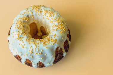 Beyaz limon jöleli kahverengi kek ve turuncu arka planda altın boncuklar.