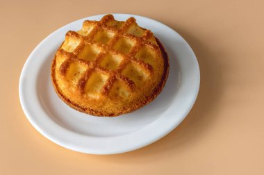 Turuncu arka planda süslenmiş kareleri olan beyaz tabakta kek, üst manzara.