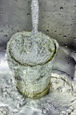 Su bardağa su sıçratır ve kabarcıklar oluşturur, yakın çekim görüntüsü