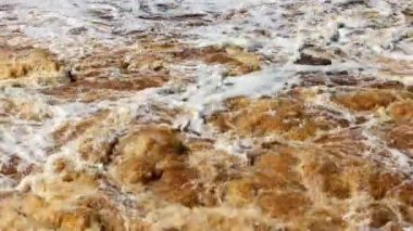 İlkbaharda sel sırasında nehirde kahverengi ve köpüklü su.