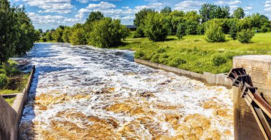 Şiddetli yağmurdan sonraki yaz nehir suyu köpük ve dalgalarla akar, uzak manzara