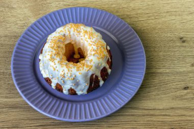 Kahverengi kek, beyaz krema ve meşe masa yüzeyindeki bir tabakta altın boncuklarla süslenmiş.