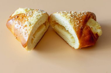 Bir tatlı ekmeği süzme peynirli. Turuncu arka planda ikiye bölünmüş. Yakın plan.